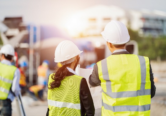 Businessman And Businesswoman Using See Plan Paper At Construction Site